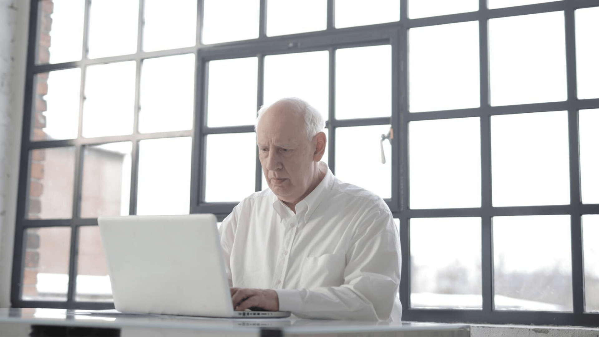 Un homme âgé assis devant un ordinateur.